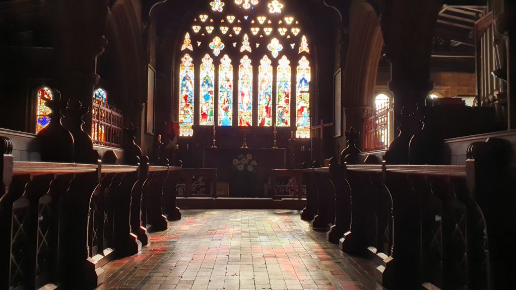 Early morning light strea,ing through the stained glass behind the high alter